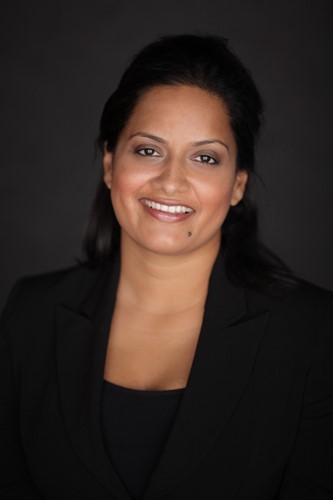 A professional woman wearing a black suit and shirt, exuding elegance and confidence.