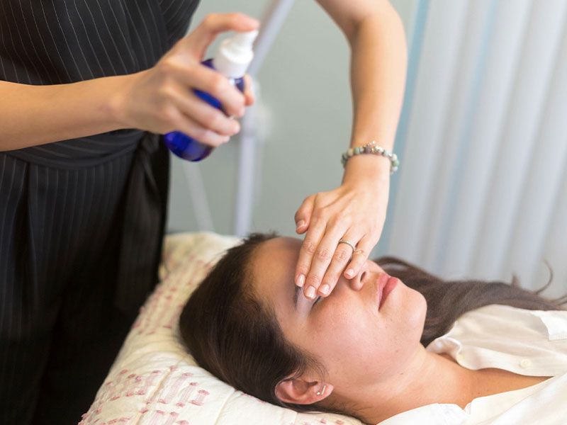 A woman having her eyes cleaned with a spray bottle.