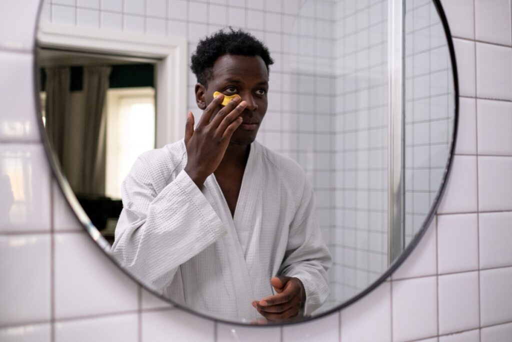 A man in a bathrobe examining his reflection in the mirror, contemplating his appearance.