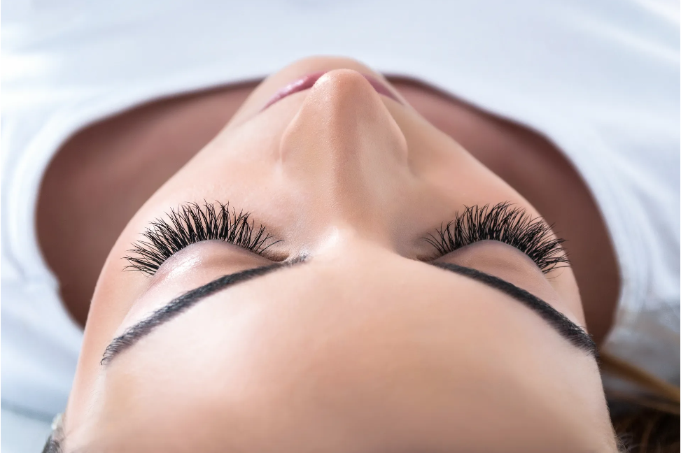 A woman with strikingly long eyelashes, looking elegant and confident.