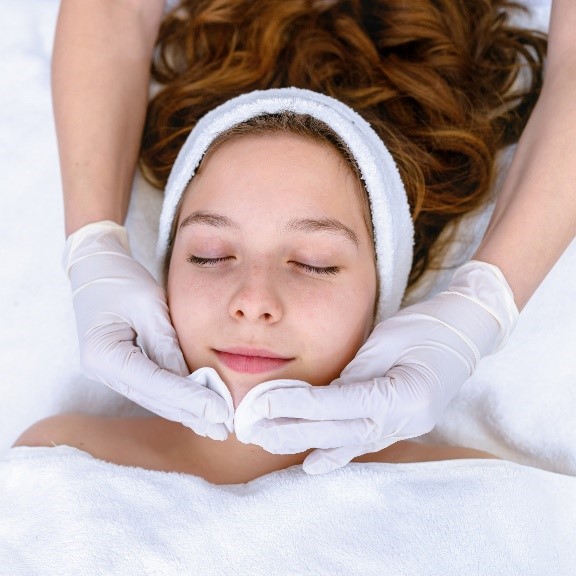 A woman enjoying a facial treatment at a spa, receiving relaxation and rejuvenation for her skin.